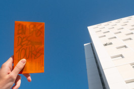 Édition d'un mémoire en design graphique sur les quartiers populaires, couverture orange, reliure cousue, prise de vue devant des immeubles