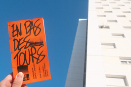 Édition d'un mémoire en design graphique sur les quartiers populaires, couverture orange, reliure cousue, prise de vue devant des immeubles